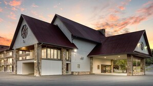 A large, modern building with a symmetrical design, featuring a prominent entrance with a covered porch and multiple windows.