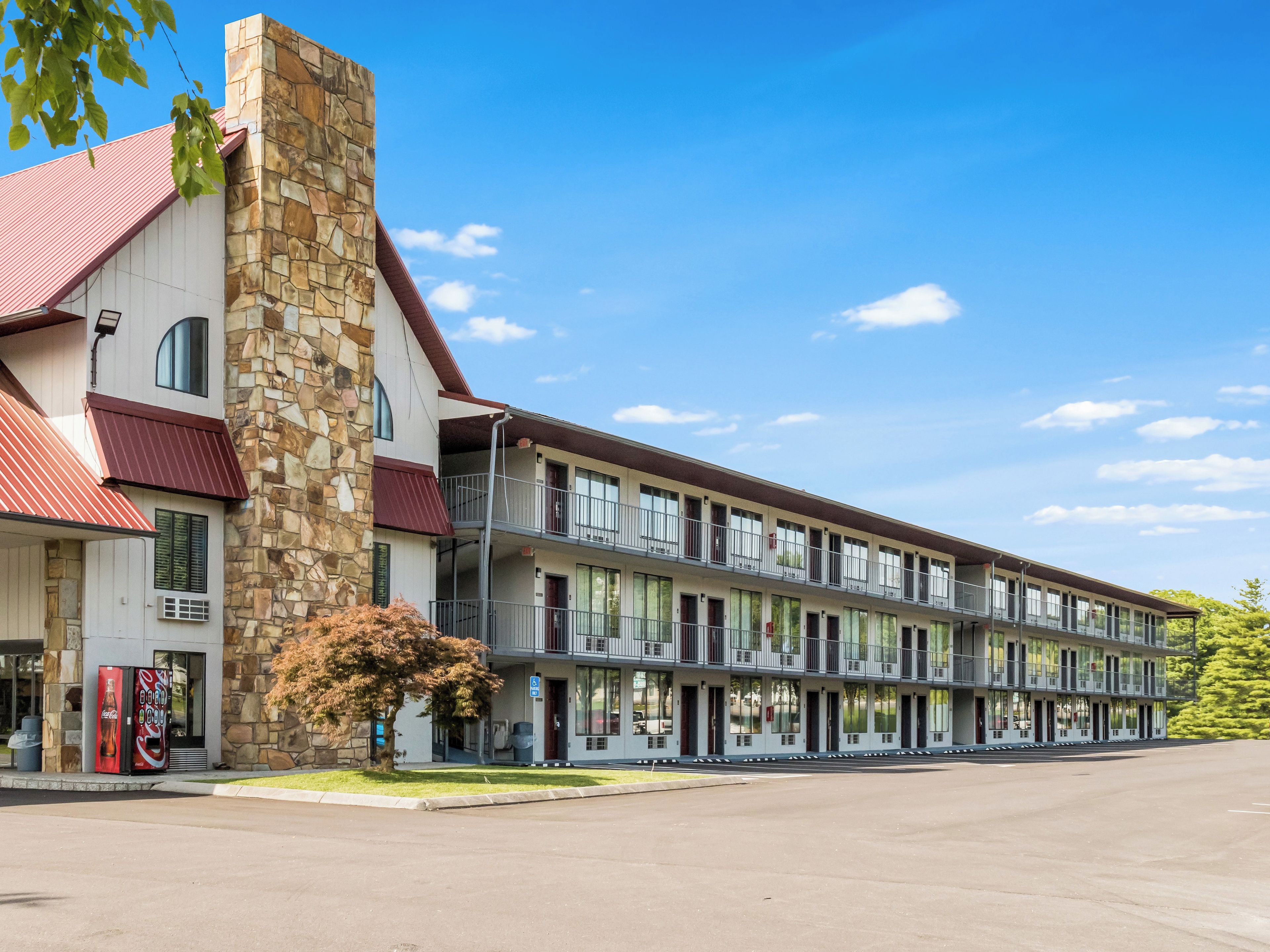 A multi-story motel with a stone facade, balconies, and a Coca-Cola vending machine.