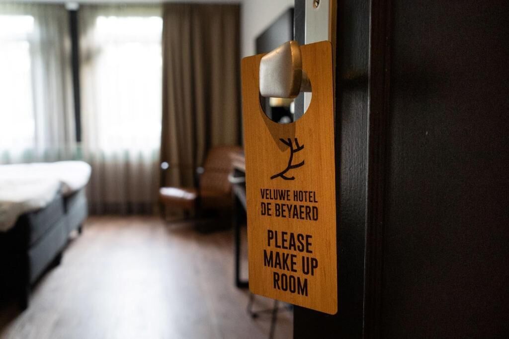 Habitación de hotel con un letrero de madera que indica que el espacio se utiliza para retoques de maquillaje.