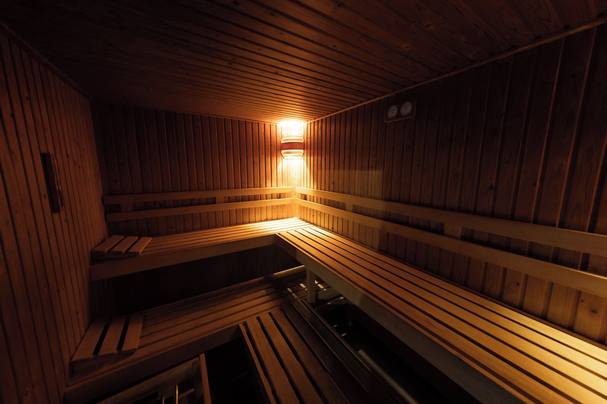 Een sauna met houten banken en een wandlamp.