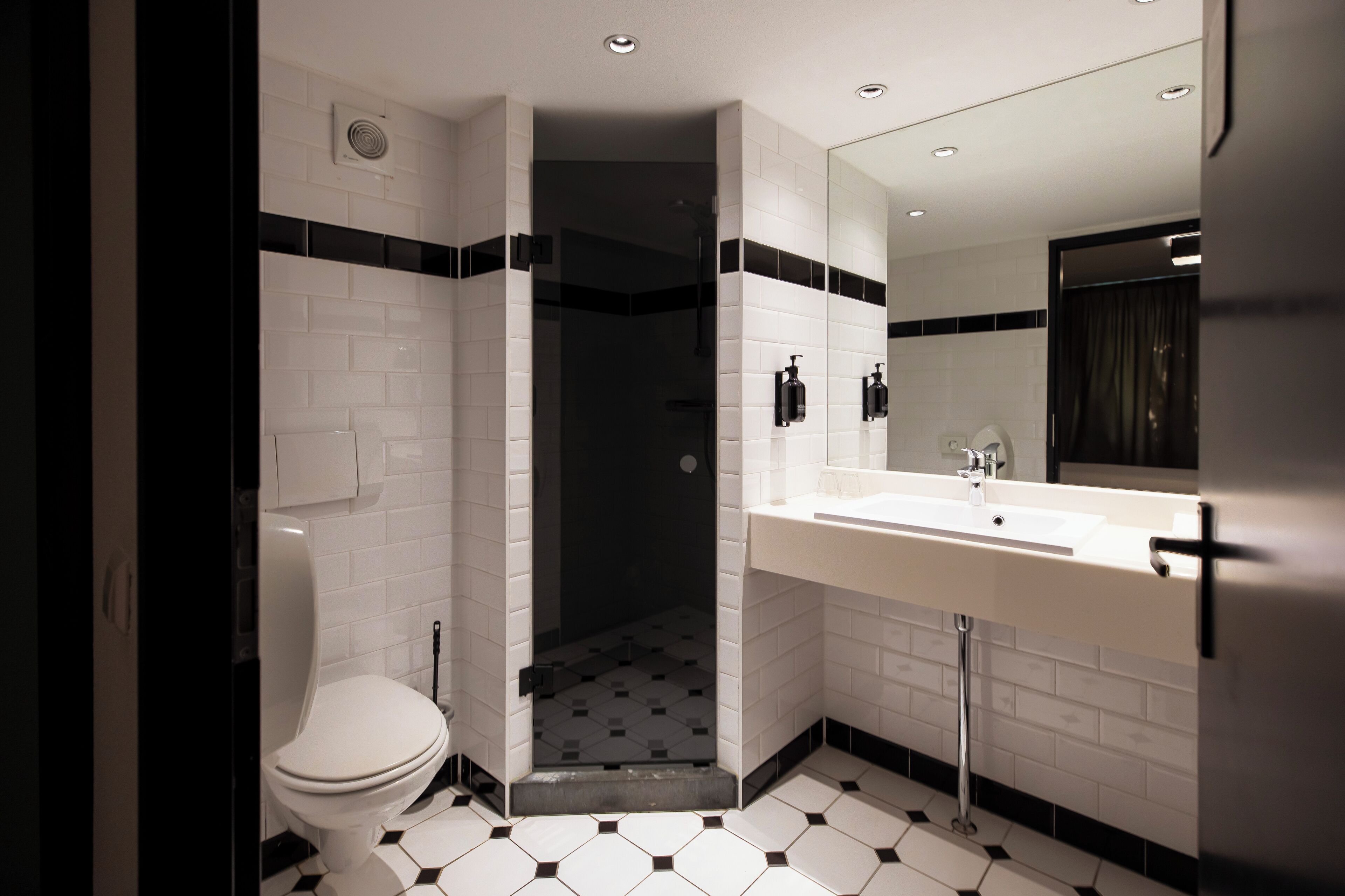 A modern bathroom with a white toilet, a shower, and a sink.
