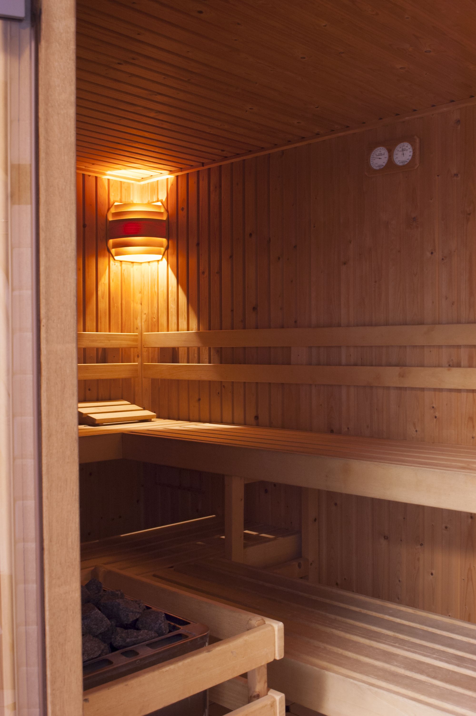 Una sauna con bancos de madera y una lámpara central.