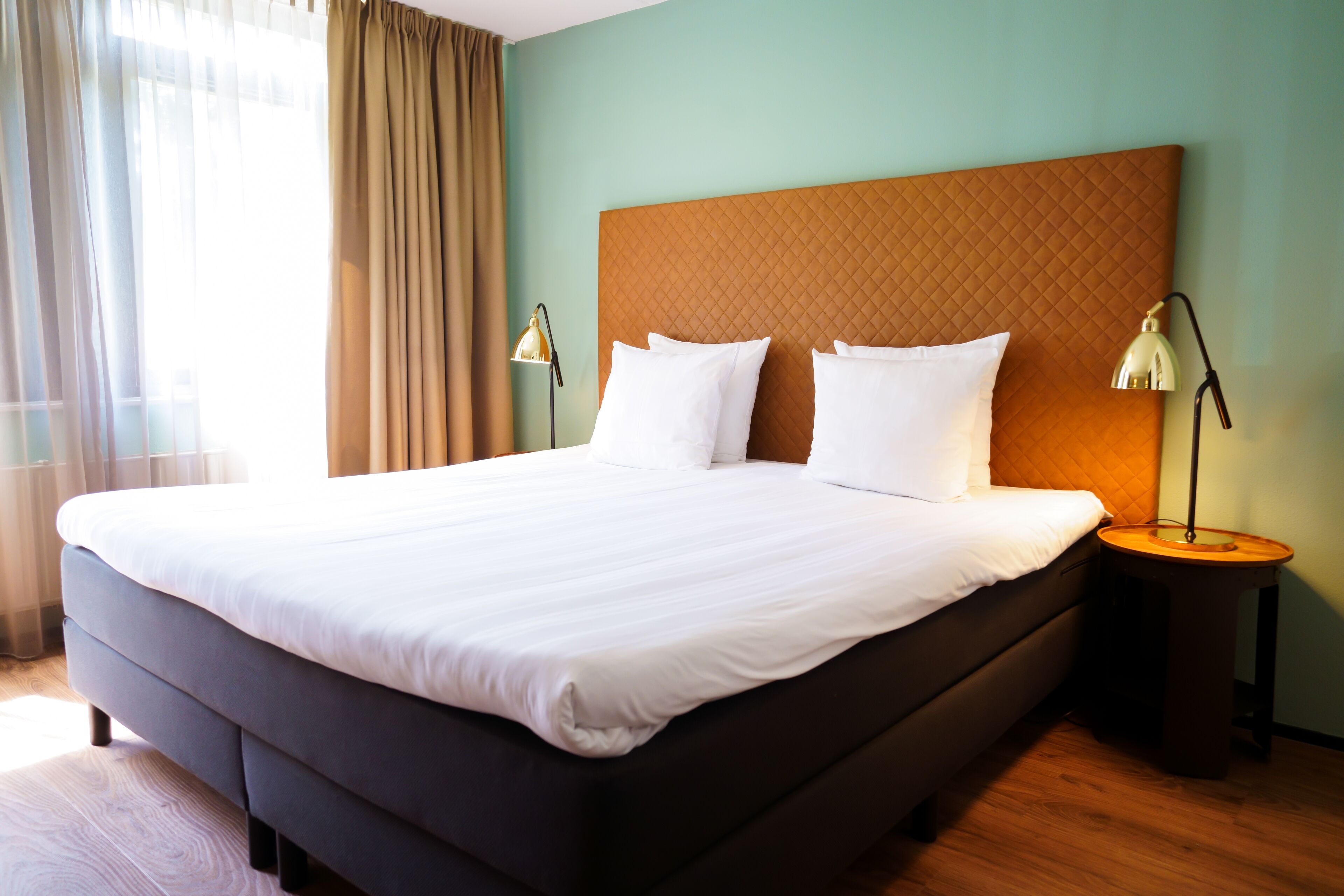 A neatly made bed with white linens, a quilted headboard, and two bedside lamps on wooden nightstands.