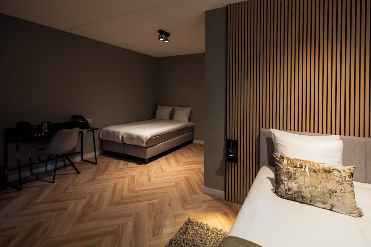 Habitación de hotel pequeña con cama, escritorio y silla.