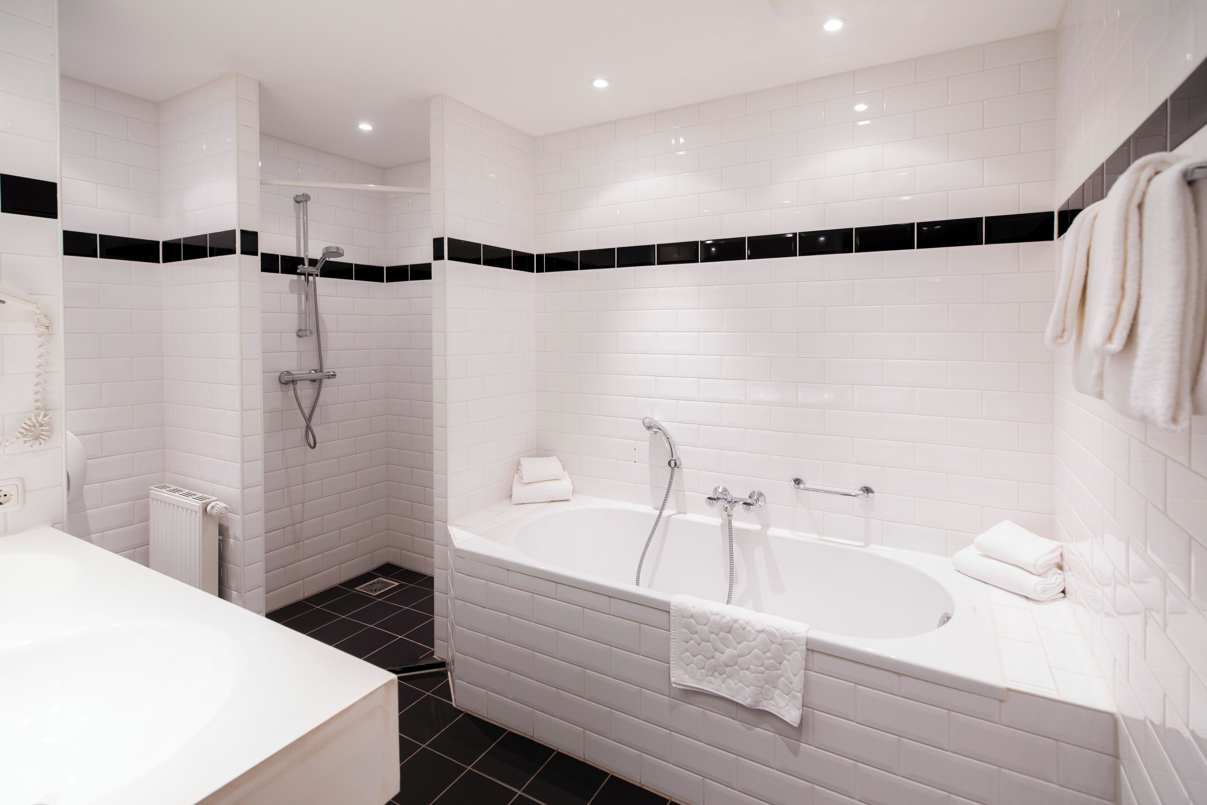 A modern bathroom with a large bathtub, a shower area, and a separate sink.