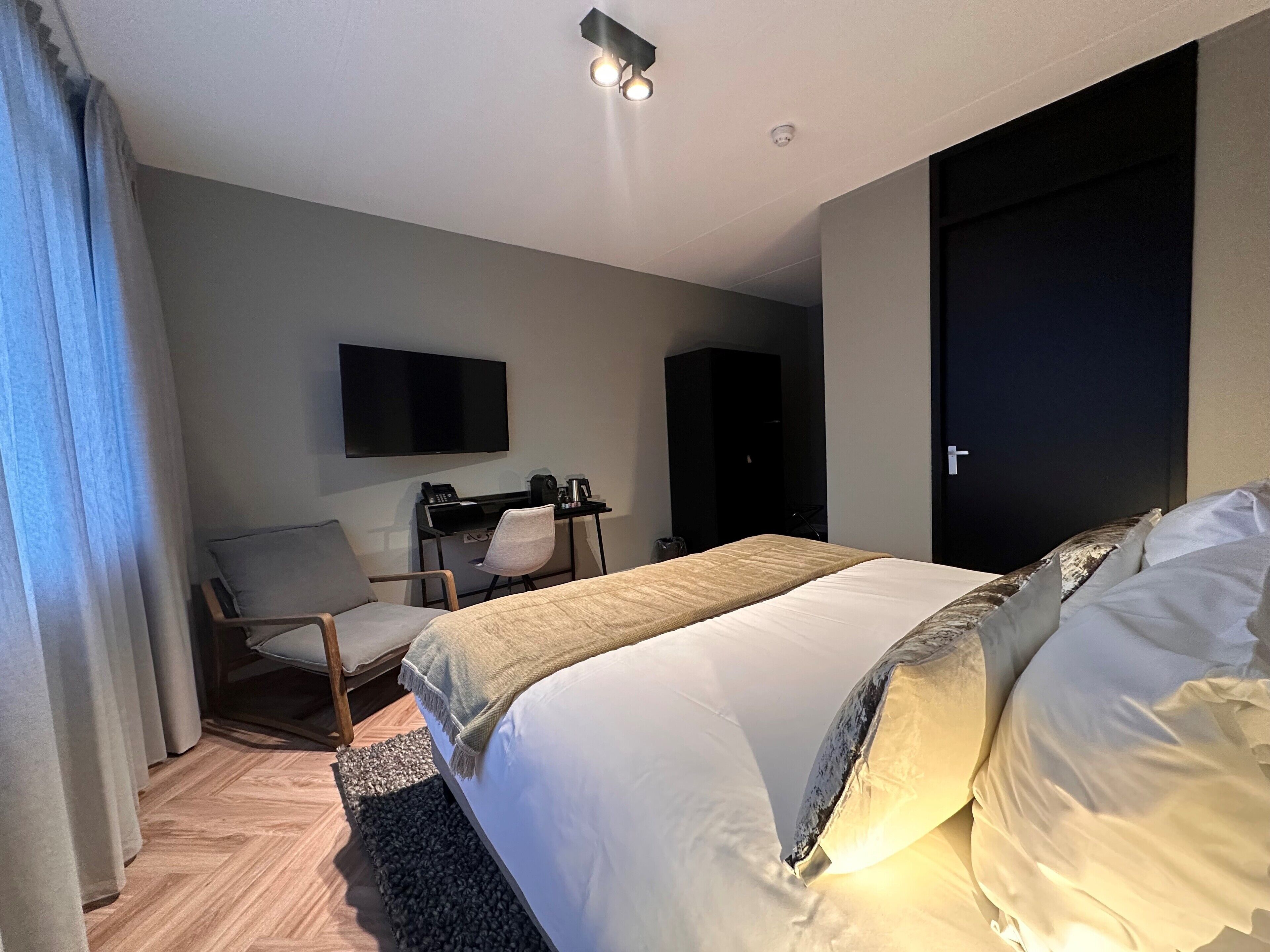 Une chambre d’hôtel comprenant un lit, un bureau avec une chaise, un téléviseur fixé au mur et une armoire.