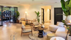 Un salon moderne comprenant un canapé, des fauteuils, une table basse et un coin repas avec une table et des chaises.