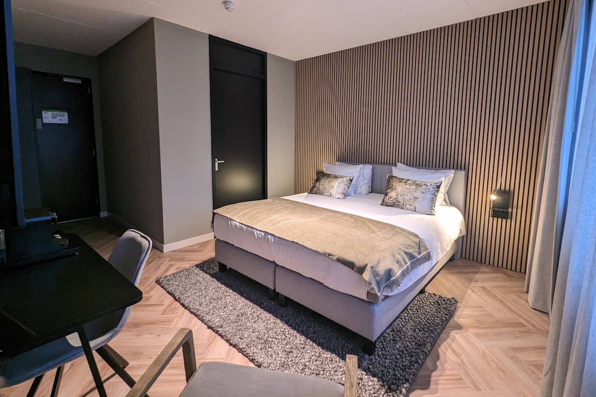 Un dormitorio moderno con cama, escritorio y silla.