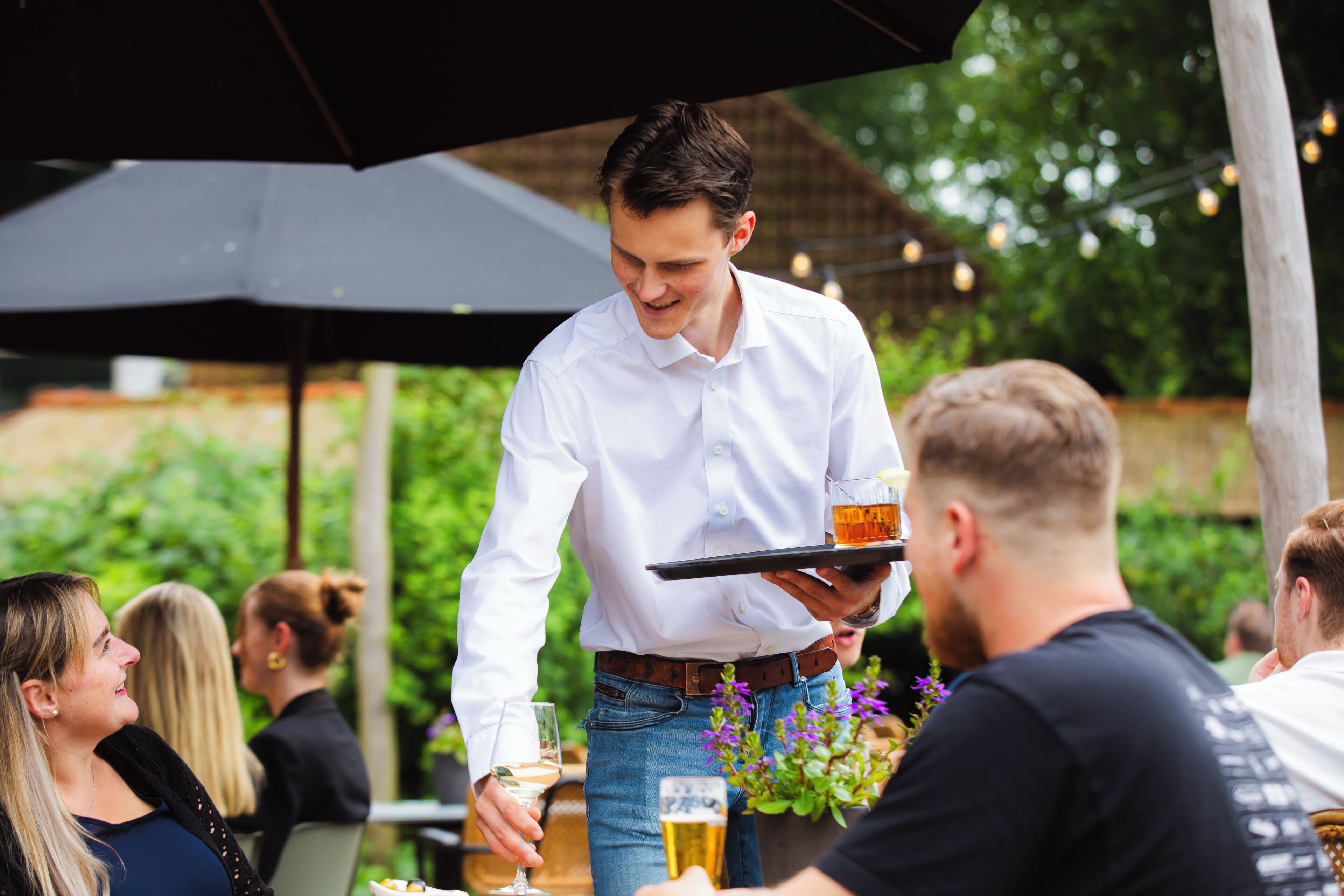 A waiter serving drinks to guests at an outdoor event.