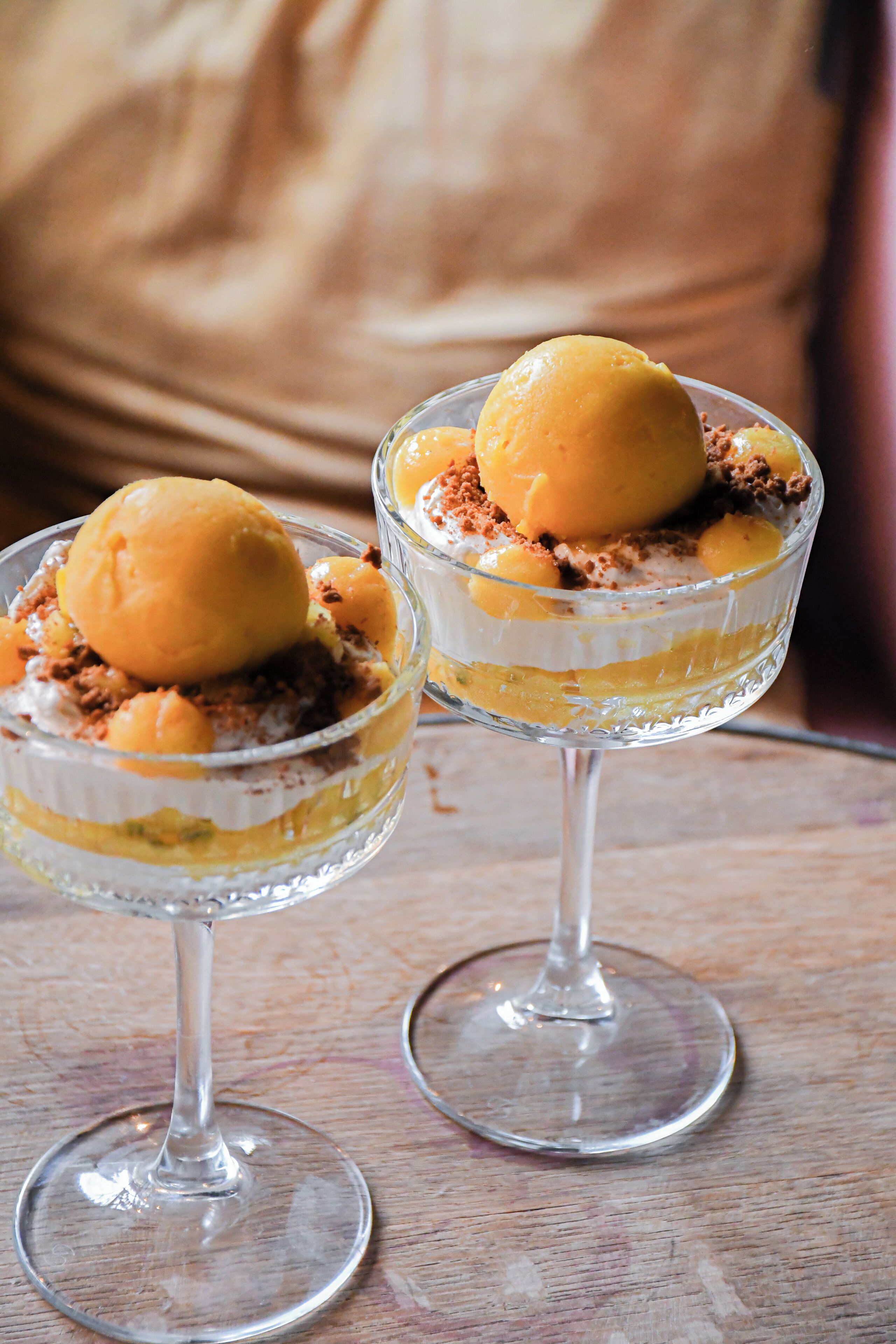 Two dessert glasses with a layered dessert and a scoop of ice cream on top.