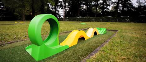 Un parque infantil con un tobogán espiral verde y un tobogán ondulado verde y amarillo.