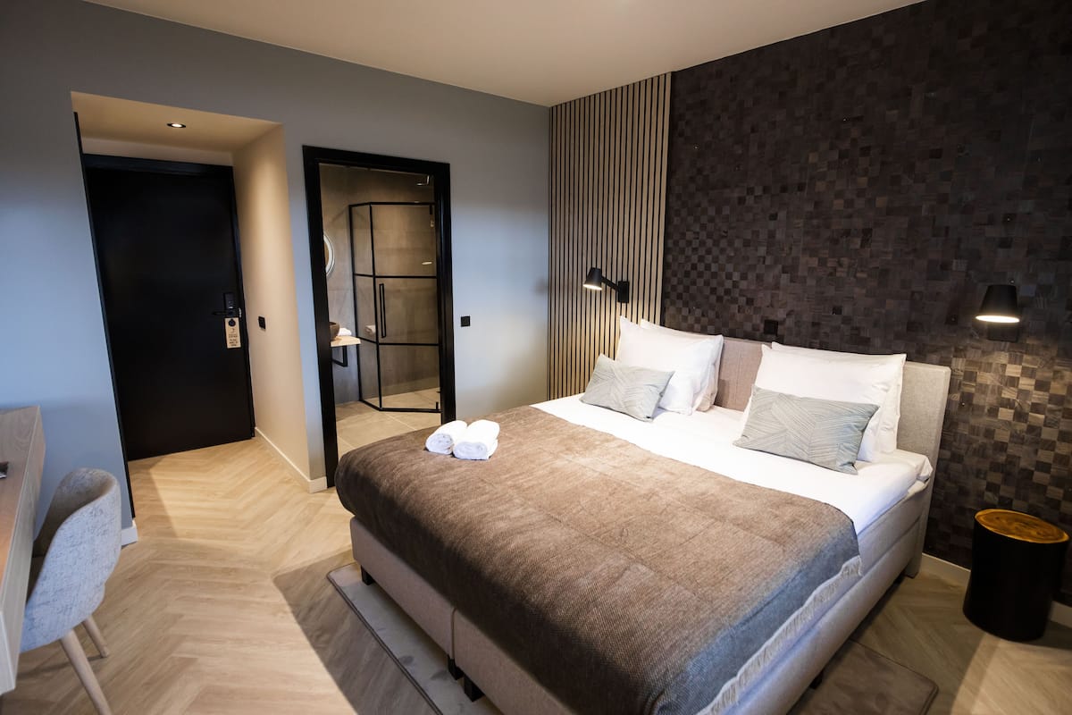 Una habitación de hotel moderna con una cama grande, un escritorio y una silla.