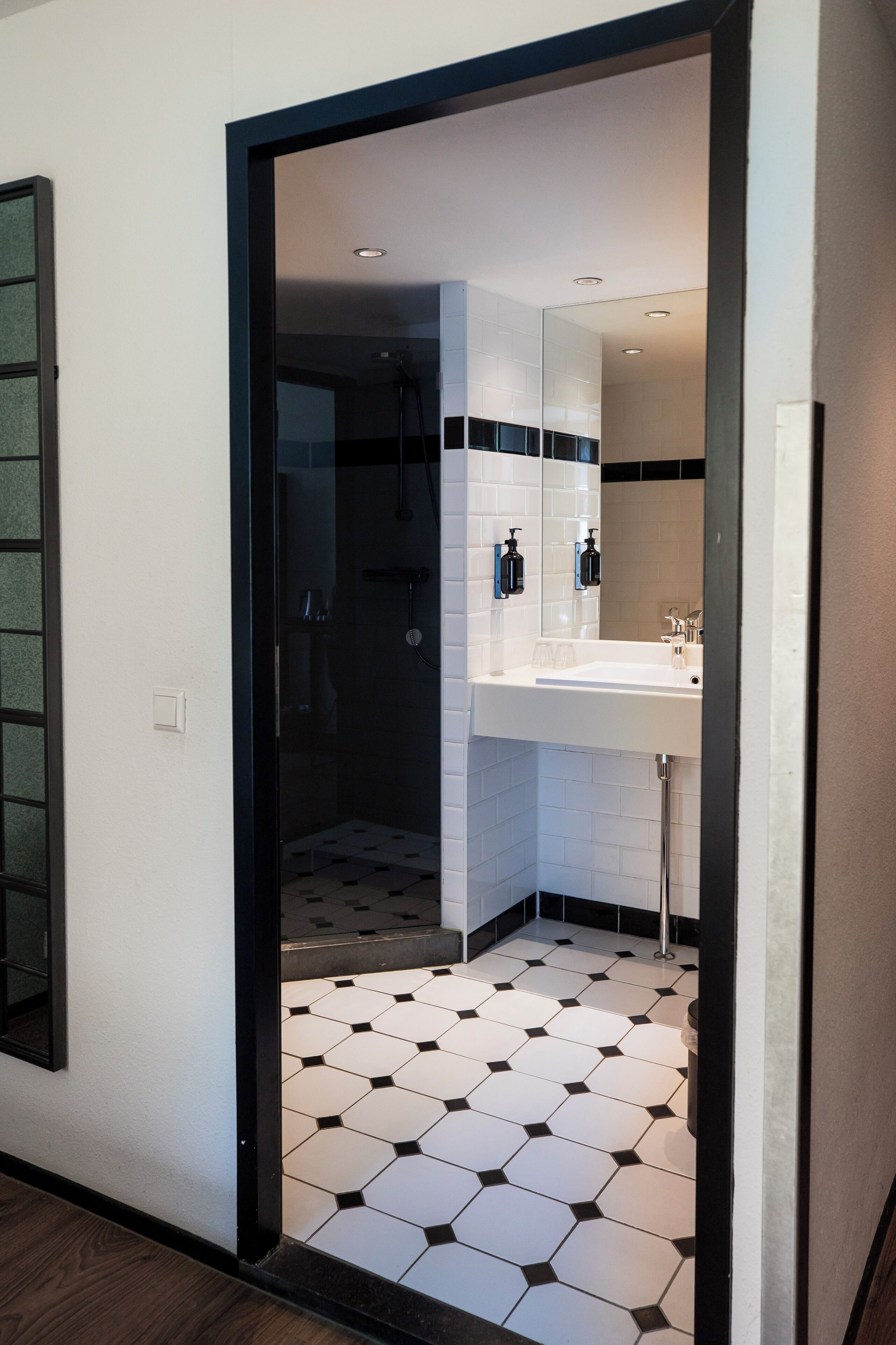 Ein modernes Badezimmer mit Duschkabine aus Glas, einem weißen Waschbecken und einem gefliesten Boden.