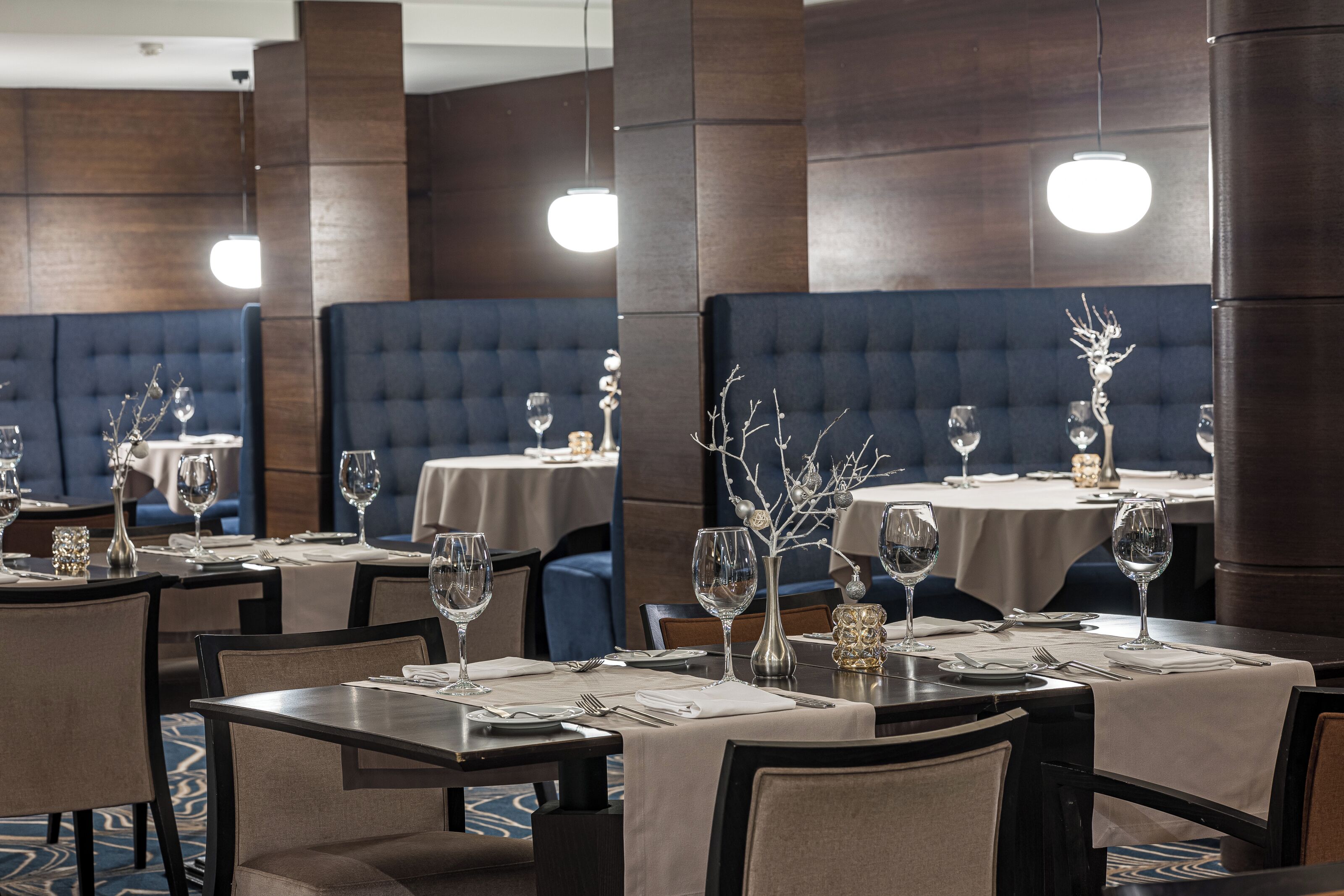 Un restaurante con mesas dispuestas para comer, que presenta paneles de madera oscura y asientos tapizados en azul.