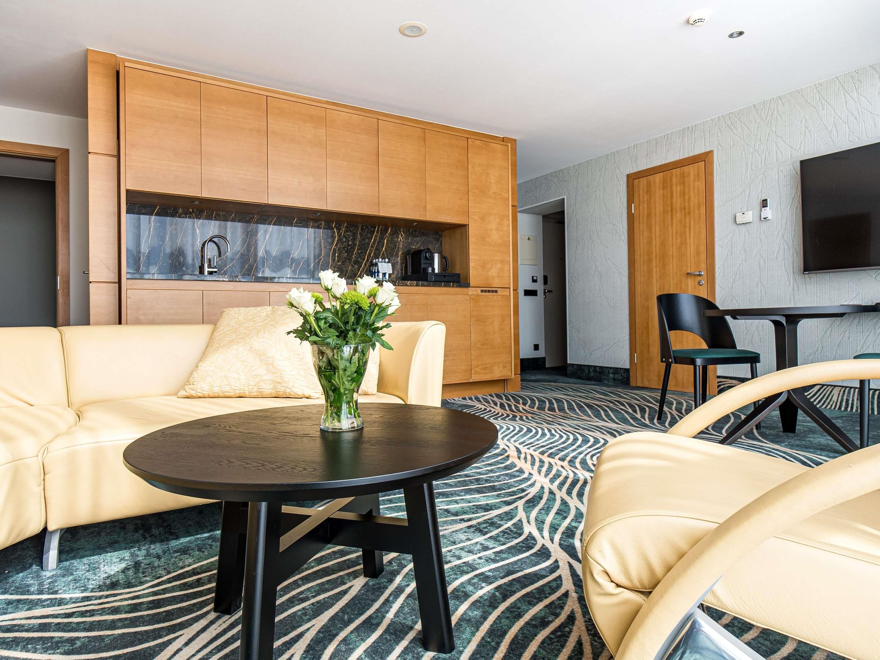 Une chambre d’hôtel moderne équipée d’un canapé, d’une table ronde, d’un téléviseur et d’un coin cuisine.