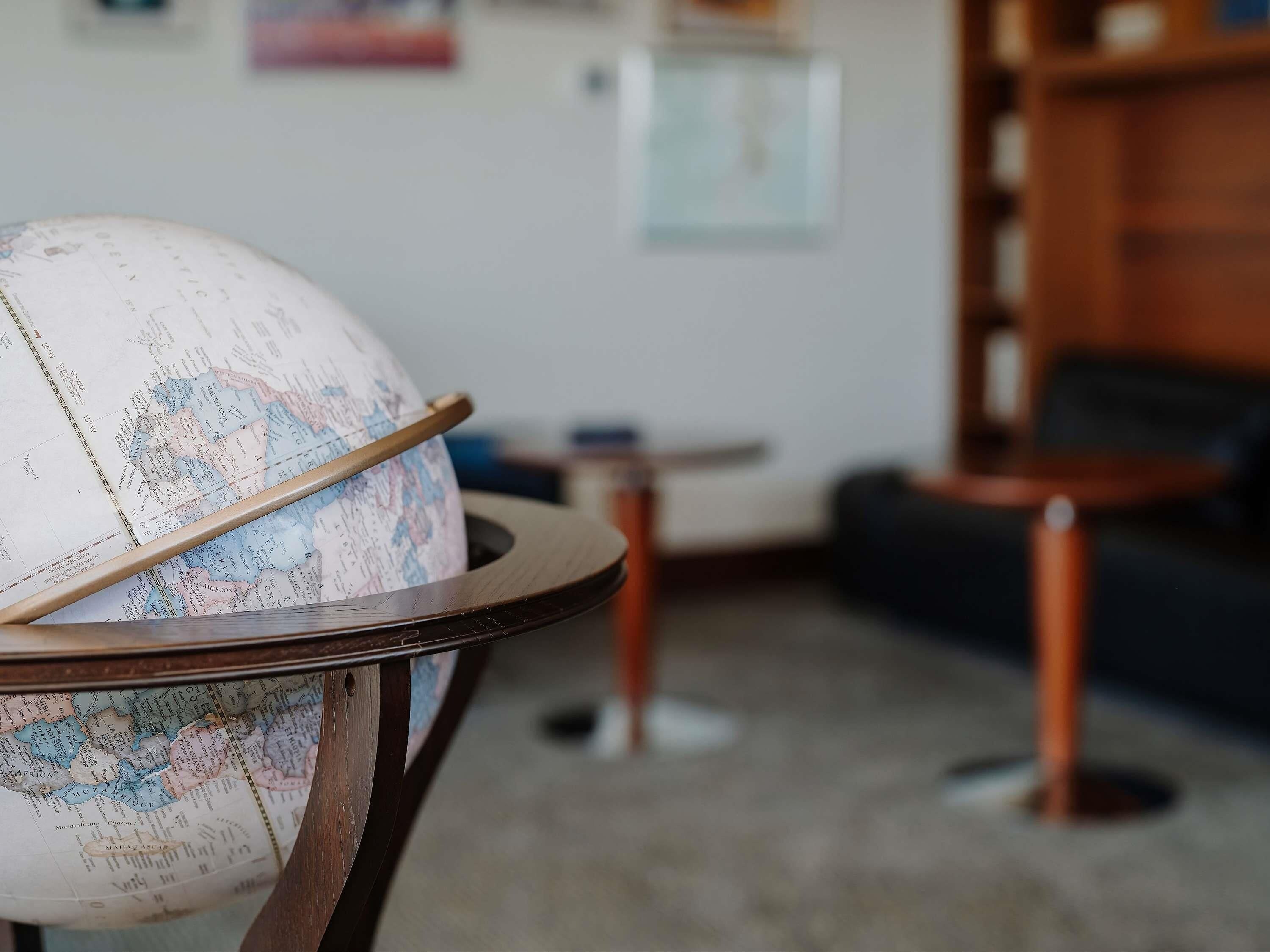 A globe on a wooden stand in a room with a couch and a small table.