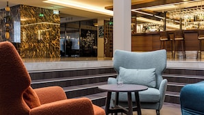 A lobby with a bar area, seating with a round table, and a staircase leading to an upper floor. - Mercure Palanga Vanagupe Resort (Palanga)