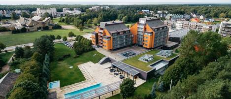 En modern byggnad med en pool på taket och ett stort grönområde.