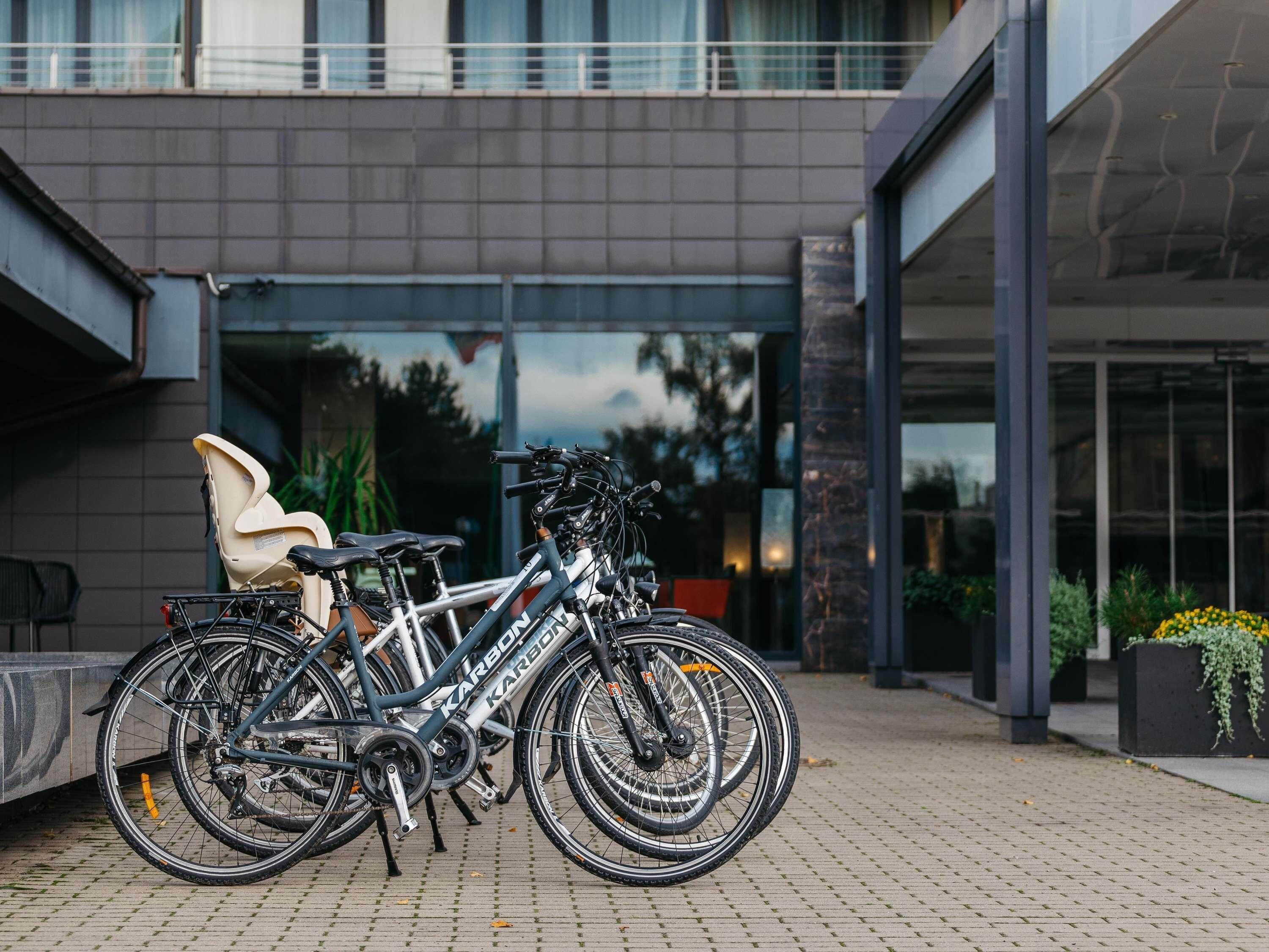 Ein modernes Gebäude mit Glastür, einem Fahrrad davor und einem Stuhl zur Linke.