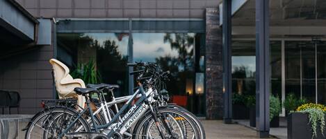 Ein modernes Gebäude mit Glastür, einem Fahrrad davor und einem Stuhl zur Linke.