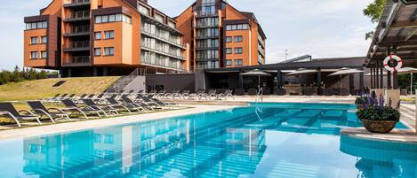A modern hotel with a swimming pool, sun loungers, and a landscaped area.