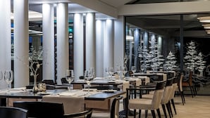 A modern restaurant with long tables, chairs, and a Christmas tree decoration. - Mercure Palanga Vanagupe Resort (Palanga)