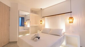 A modern hotel room with a large bed, bedside tables, a mirror, and pendant lighting. - Hotel Tropical Inn (Cartagena)