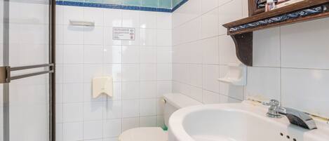 Un baño con inodoro, lavamanos y zona de ducha.