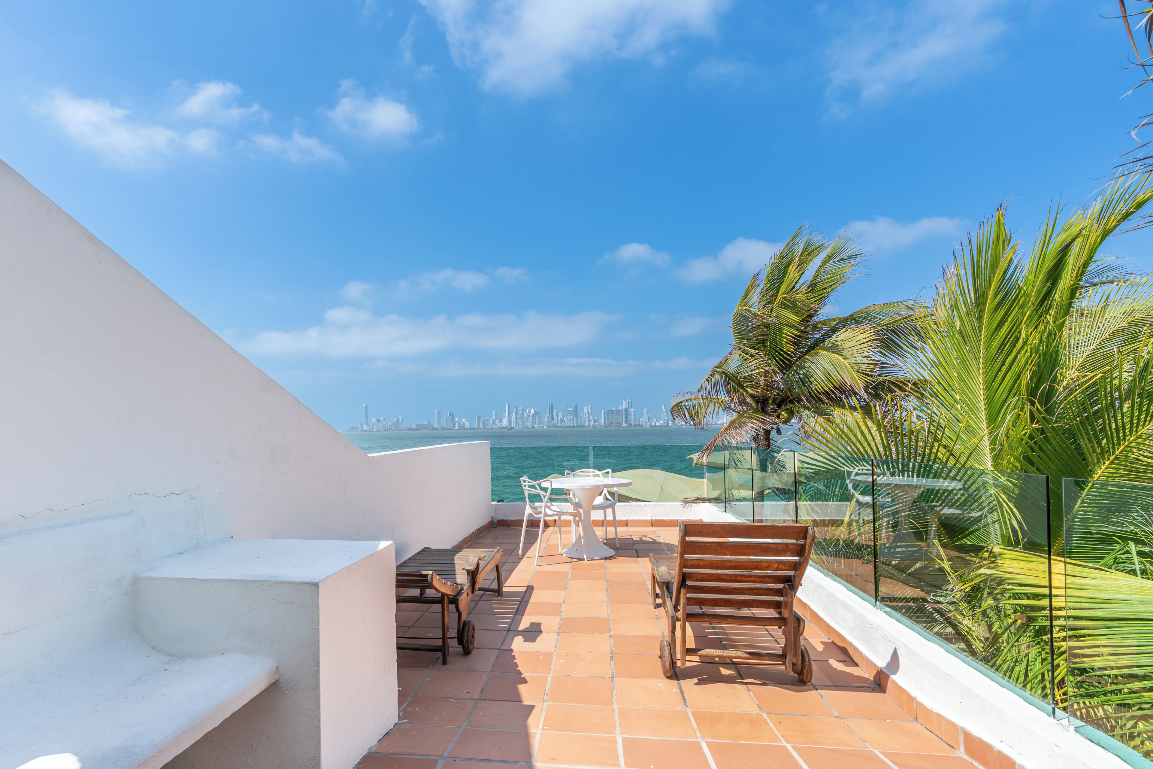 Una terraza en la azotea con vistas al horizonte de la ciudad, una mesa con sillas y un banco de madera.