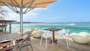 A wooden deck with outdoor seating, a table, and a large umbrella providing shade. - Hotel Tropical Inn (Cartagena)