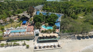 An aerial view of a hotel with a swimming pool, beach area, and surrounding tropical vegetation. - Hotel Tropical Inn (Cartagena)