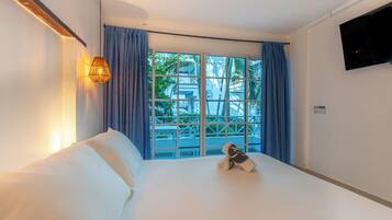 Quarto de hotel com cama, televisão e janela com cortinas.