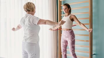 A person stretching with a resistance band in a room with a wooden rack and a window with blinds.
