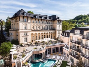 Een groot, meerhoog hotel met een zwembad, terras en uitzicht op het omliggende landschap.