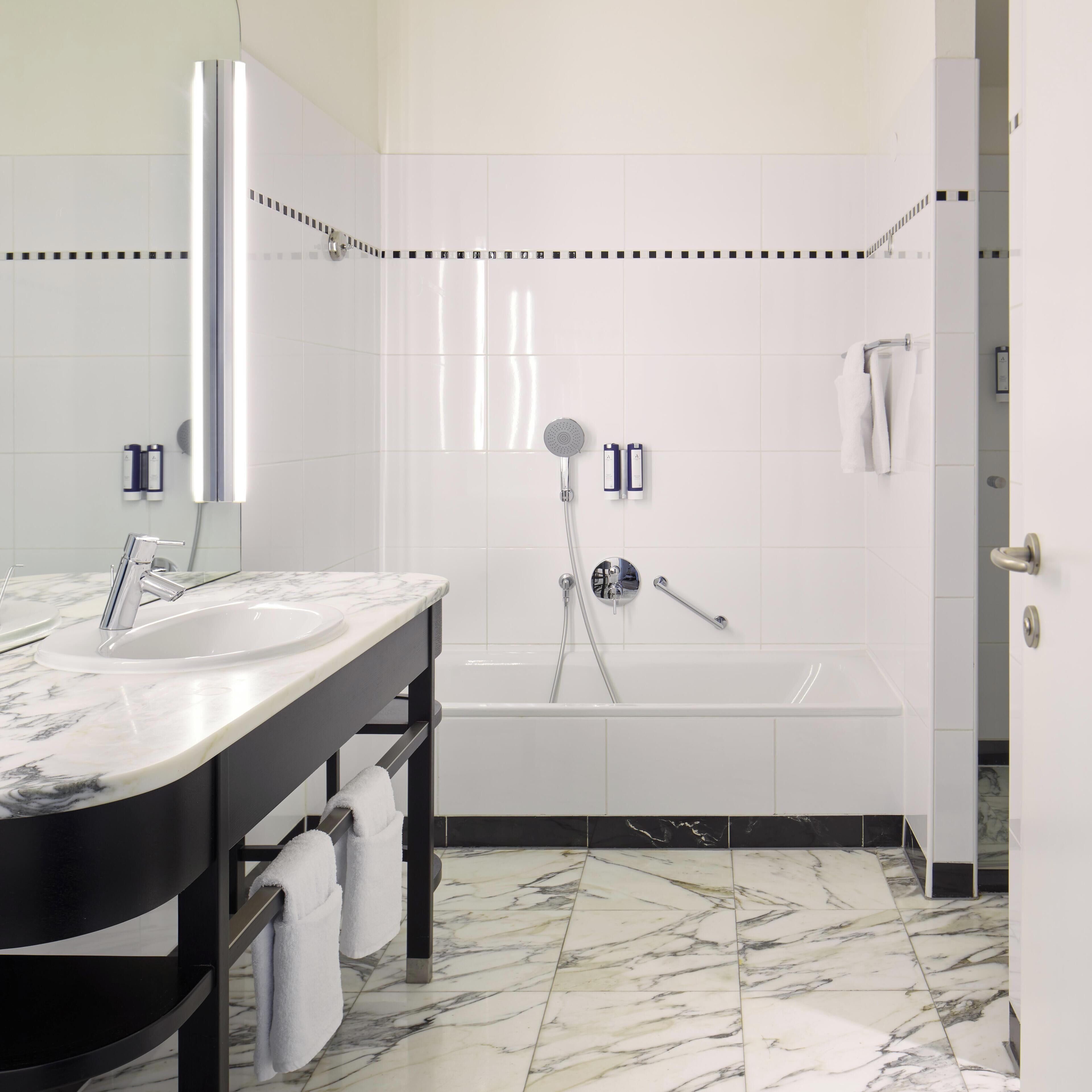 A modern bathroom with a marble sink, a bathtub, and a shower.