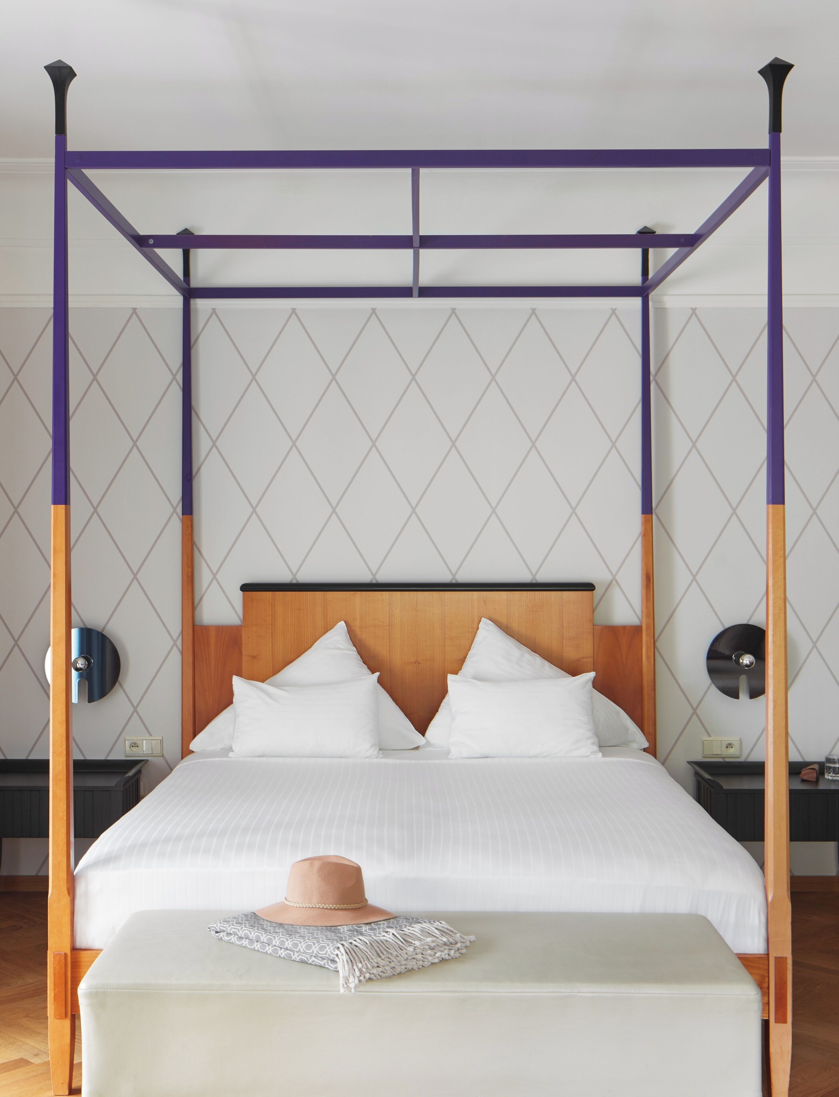 A four-poster bed with a wooden headboard, white bedding, and a bedside table with a lamp.