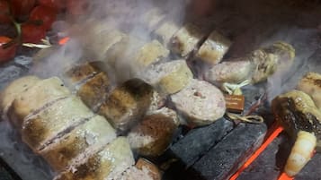 A grill with various meats and vegetables being cooked over charcoal.