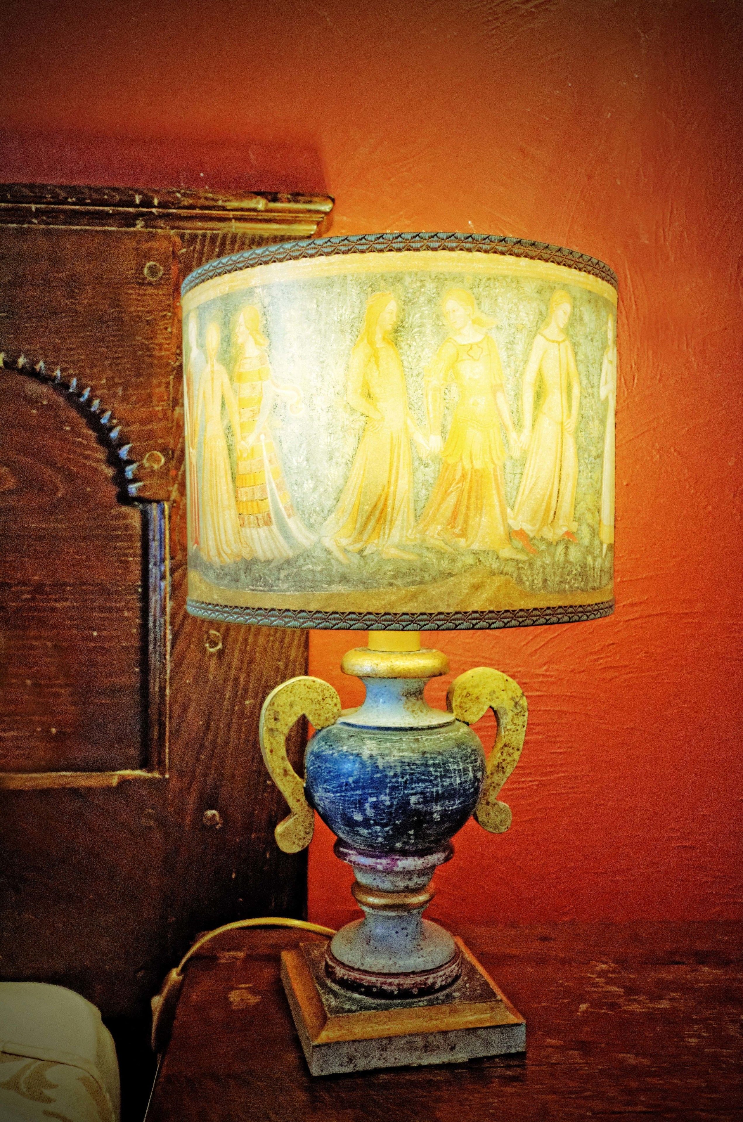 Una lámpara con pantalla decorativa y base azul.
