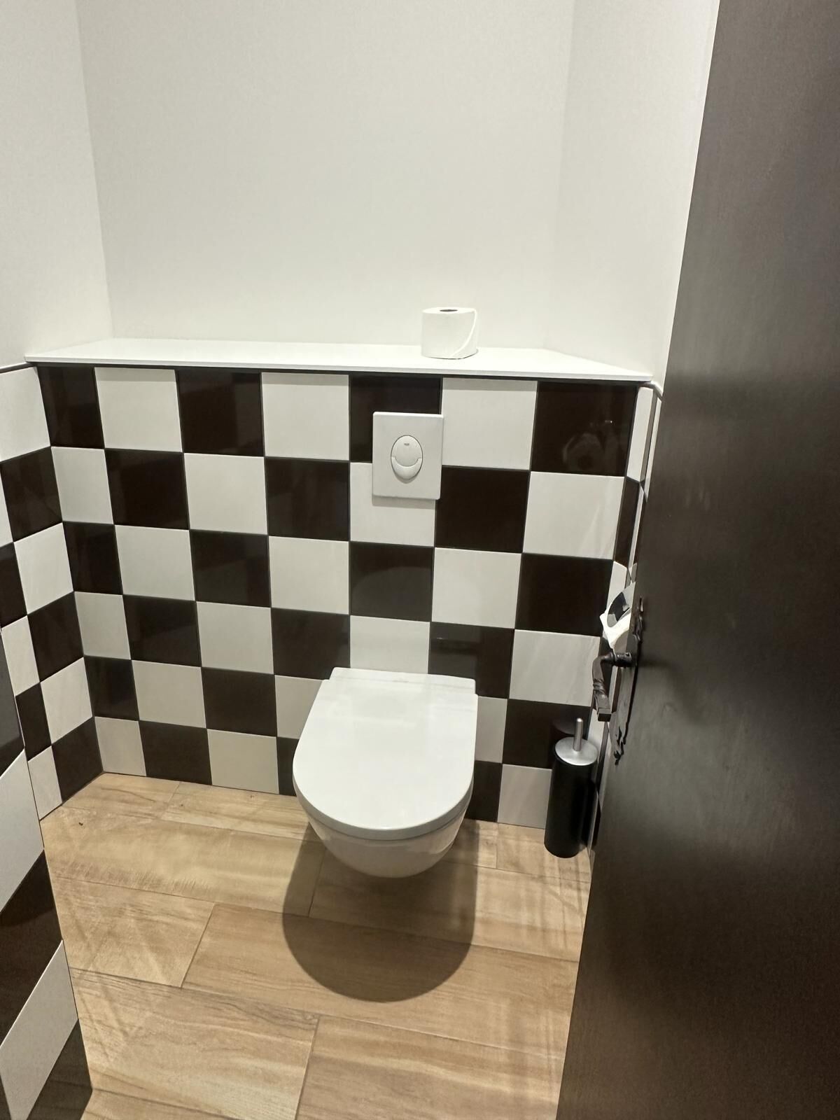 A small bathroom with a toilet, a hand dryer, and a paper towel dispenser.