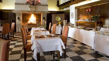 Un comedor con mesas dispuestas para una comida, una chimenea y una araña.