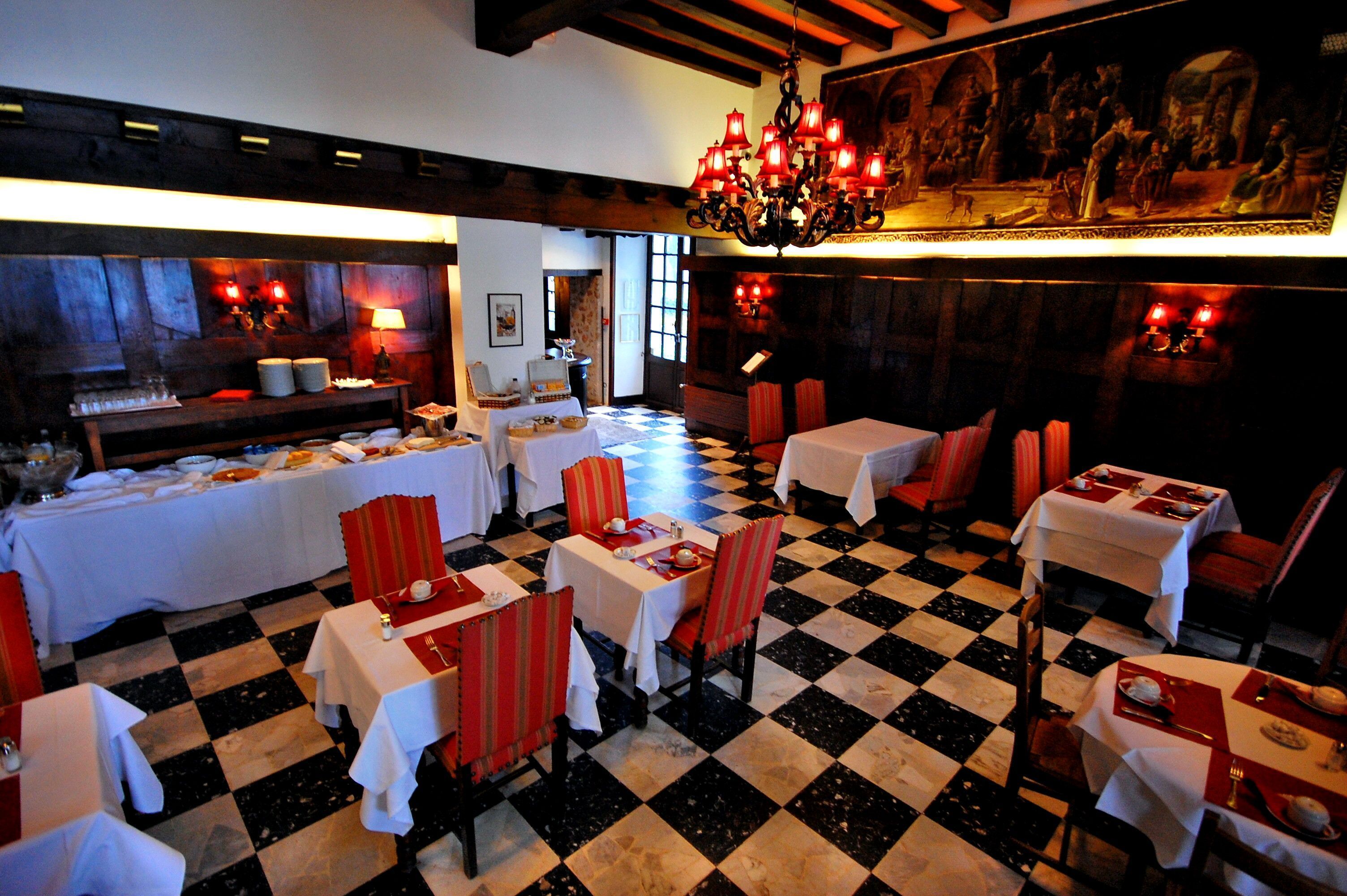 Un restaurante con suelo de cuadros, mesas blancas y rojas y un candelabro.