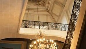 Uma escadaria com guarda-corpo de ferro forjado e um candelabro.