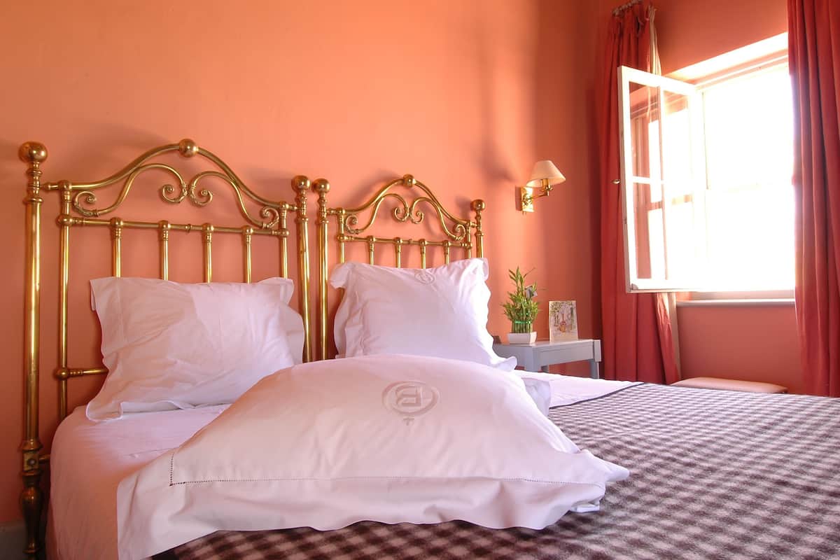 A bed with a gold headboard, white bedding, and a checkered blanket.