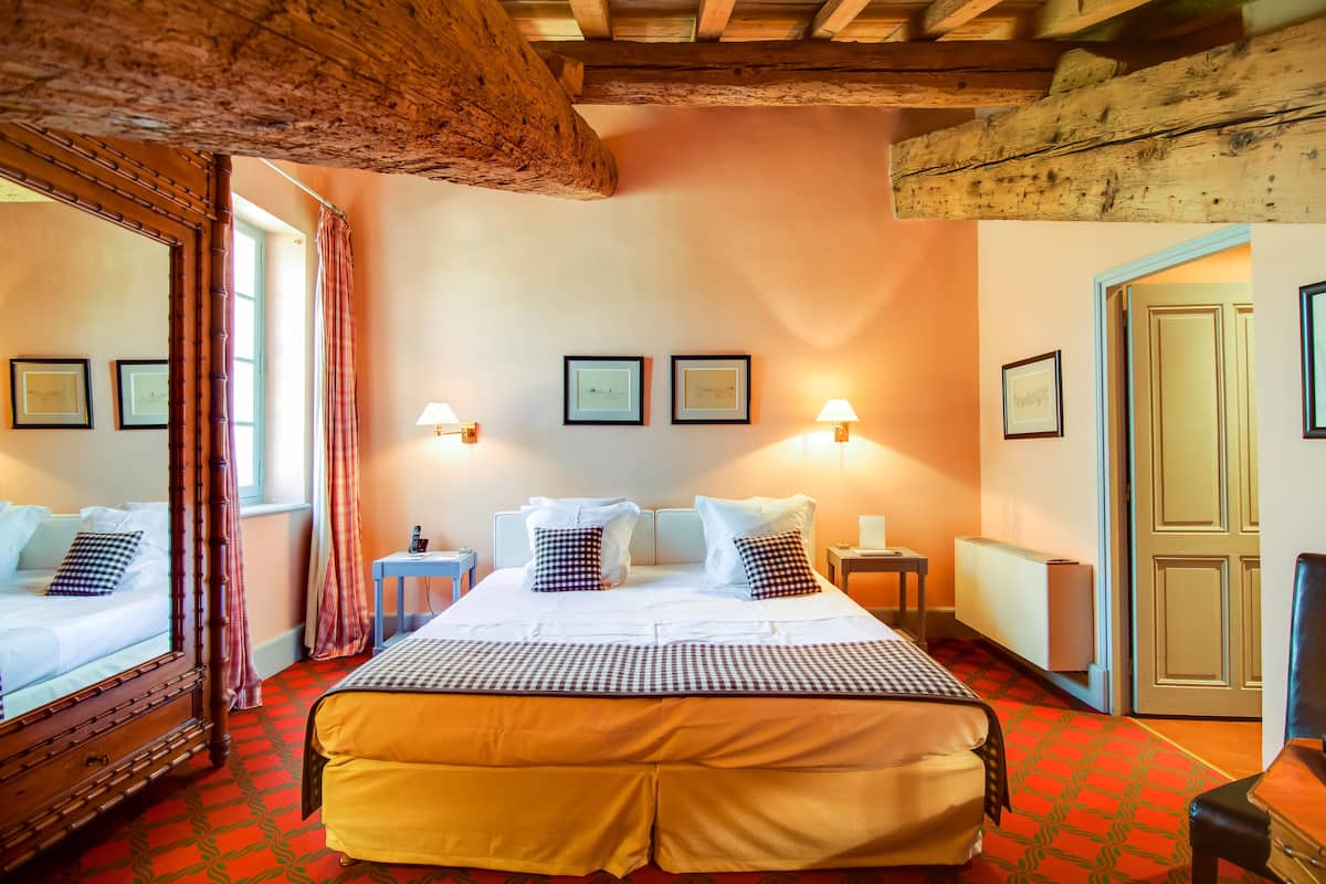 A hotel room with a large bed, a wooden ceiling, and framed pictures on the wall.