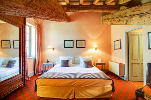 Una habitación de hotel con una cama grande, techo de madera y cuadros en la pared.