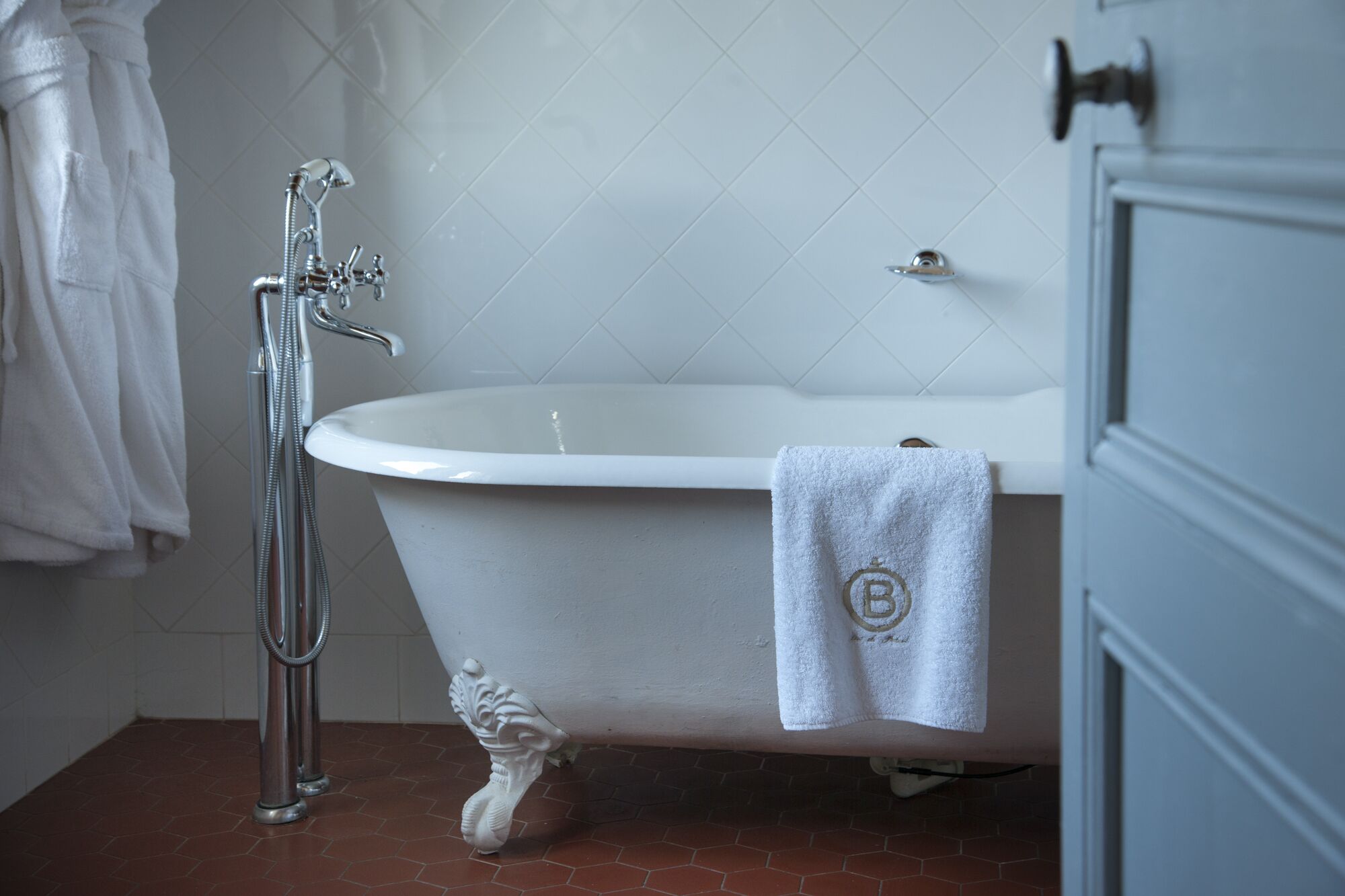 Un bagno con una vasca da bagno bianca, una doccia e un asciugamano appeso al muro.