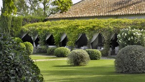 A courtyard with a tiled roof, covered walkways, and neatly trimmed bushes. - Le Mas De Peint (Arles)