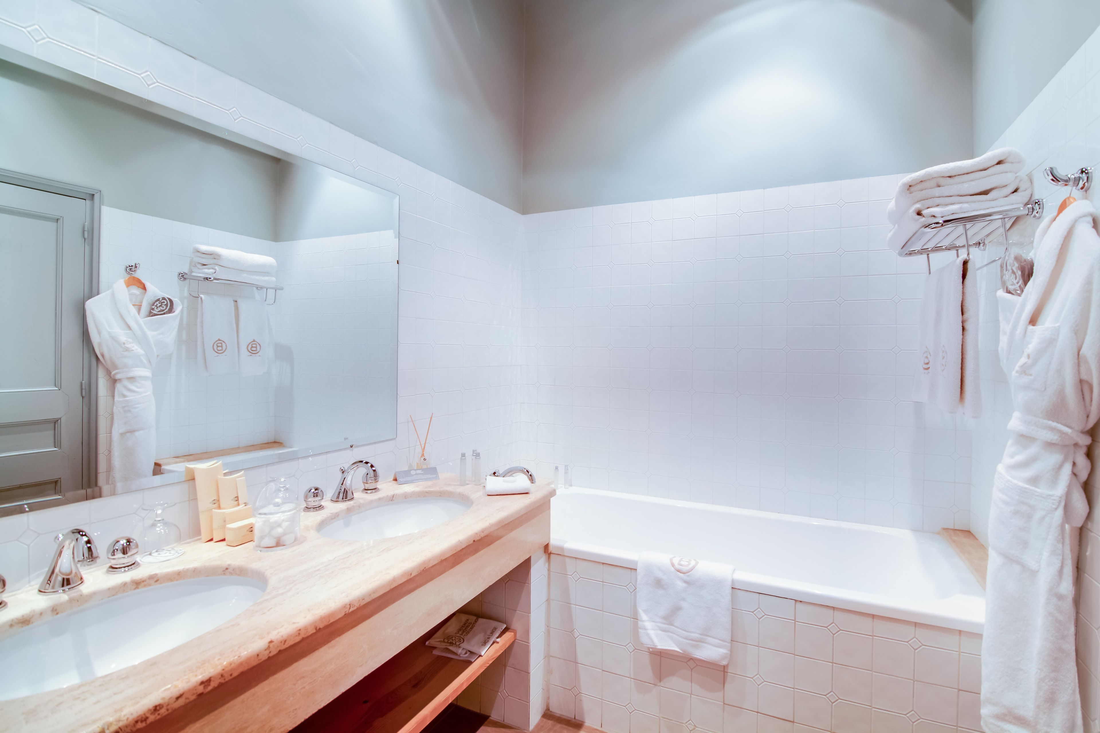 Un baño con dos lavamanos, un espejo grande y una bañera.