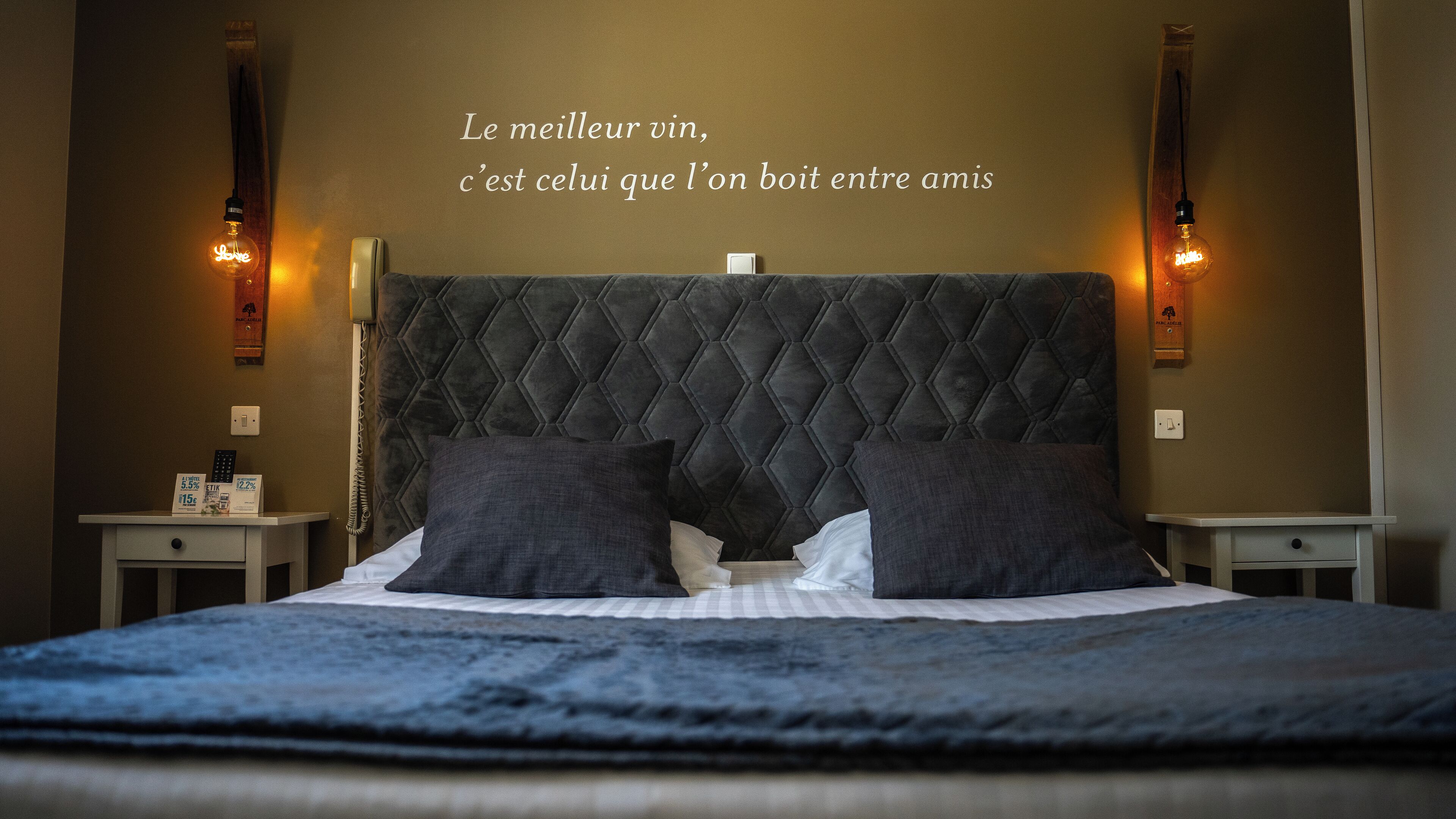 A bedroom with a tufted headboard, two bedside tables, and a bed with pillows.