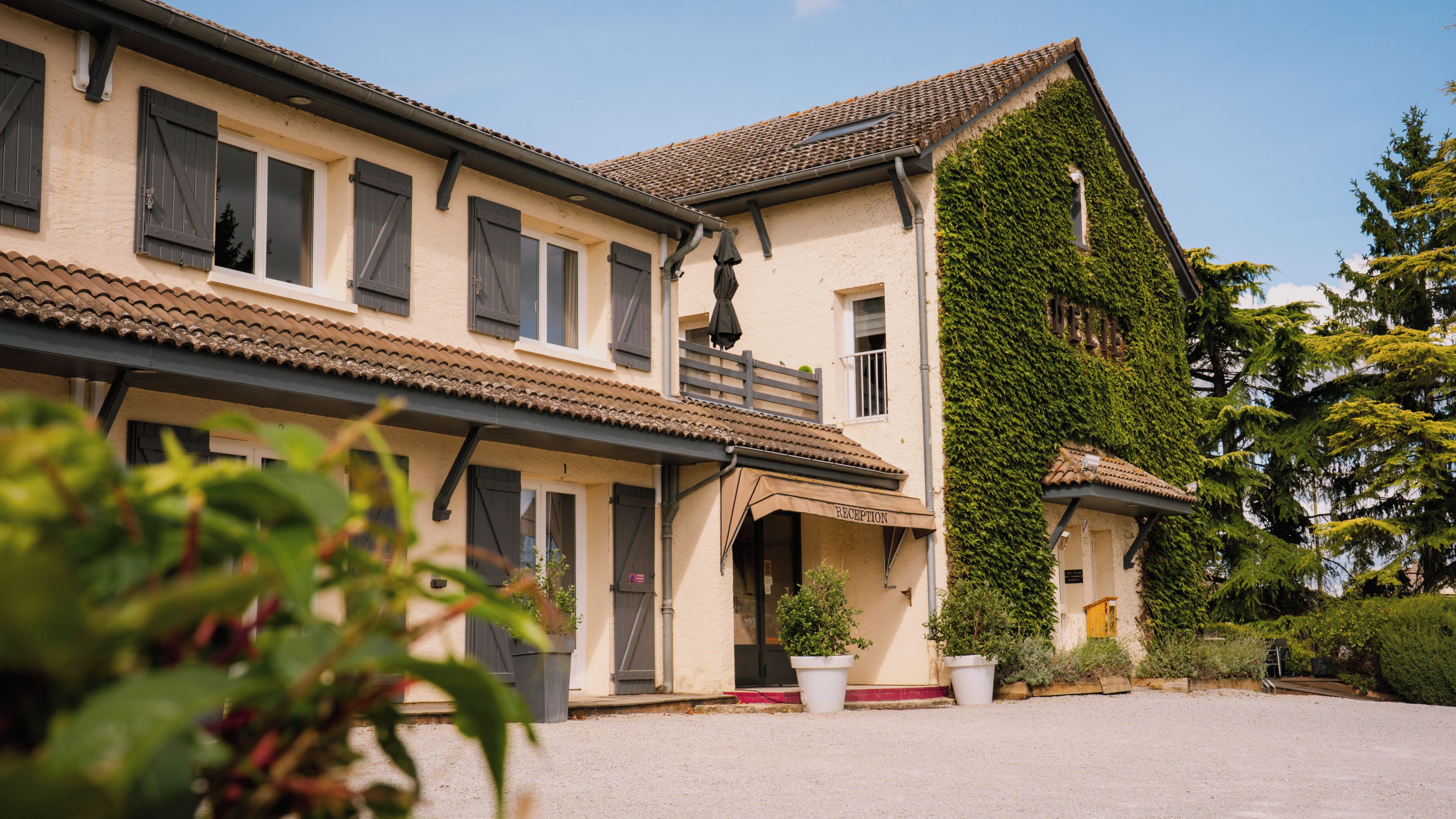 Un bâtiment à deux étages, doté d’un toit en tuiles, d’un balcon et d’un espace d’accueil.